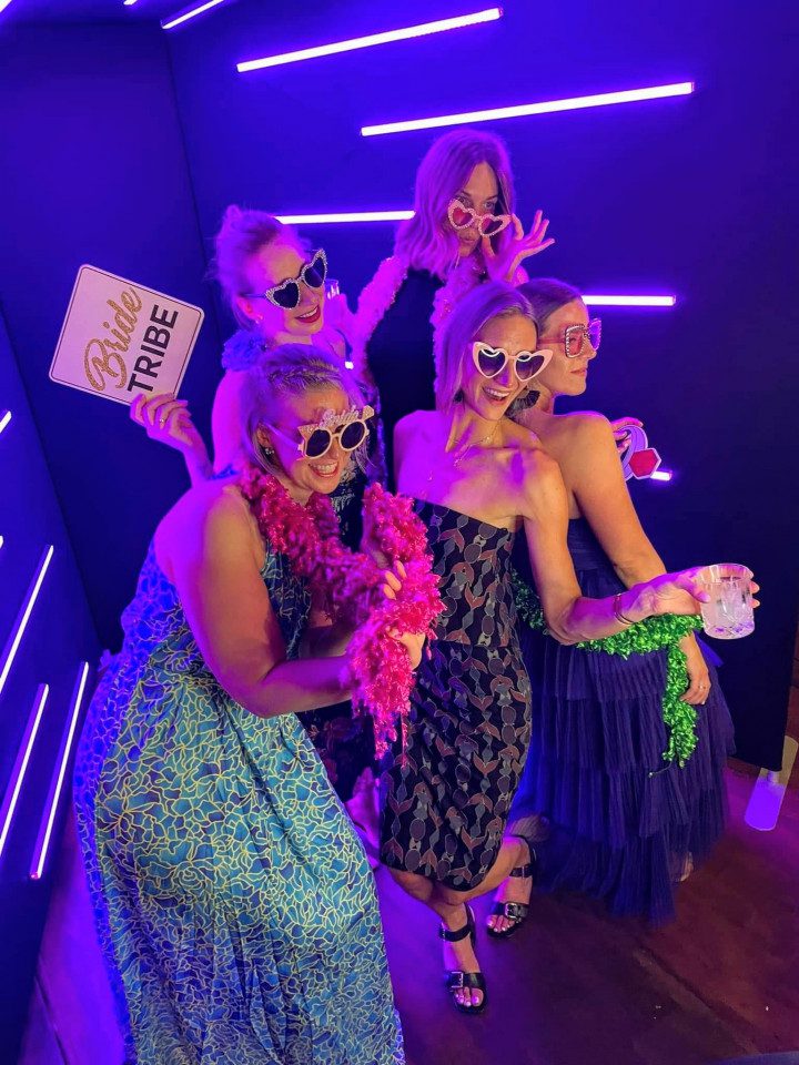 Guests posing in a high-fashion Vogue photo booth with dramatic lighting for a luxury wedding in Denver