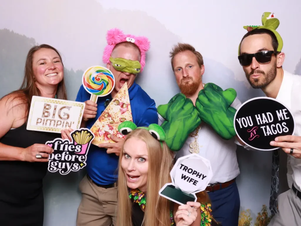 Wedding guests posing with fun props inside photo booth at reception in Colorado