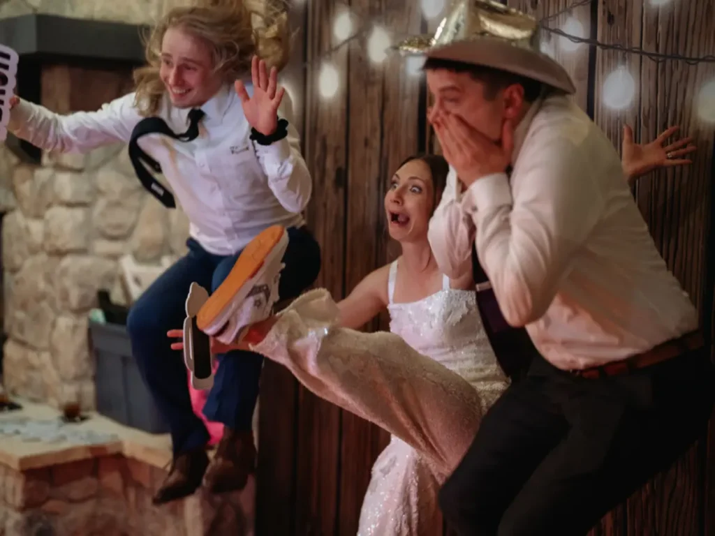 Bride and wedding guests posing with props inside photo booth at Brookside Gardens in Berthoud CO